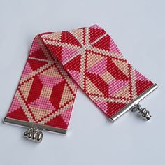 two red and white cross - stitch purses with silver clasps on each side