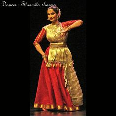 a woman in a red and gold dress on stage with her hands behind her back