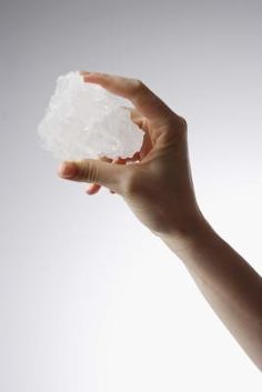 a person's hand holding cotton in front of a white background with no image on it