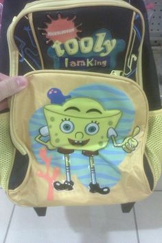 a person holding up a yellow backpack with an image of a cartoon character on it