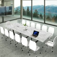 a table with chairs and a laptop on it in front of large windows overlooking mountains