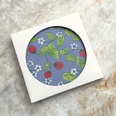 a paper plate with strawberries and flowers on it sitting on a marble surface next to a piece of paper