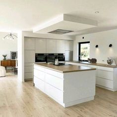 a large kitchen with white cabinets and wood floors