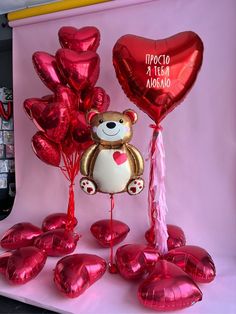 a teddy bear surrounded by balloons and heart - shaped hearts on a pink background with the words i love you in spanish