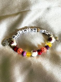 a bracelet with beads and charms that say breaking dawn on the front, sitting on a white satin surface