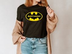 a woman wearing a batman t - shirt with the word mom on it