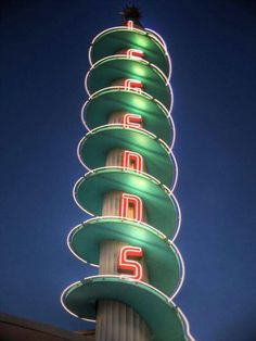 the top of a tall tower with neon signs on it