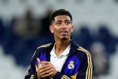 a soccer player with his hand on his chest and looking up at the sky while wearing a blue and yellow jacket