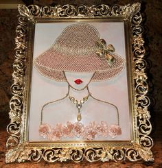 an ornate gold frame with a woman's face wearing a pink hat and necklace