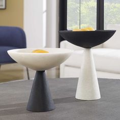 two white and black bowls sitting on top of a table next to a blue chair