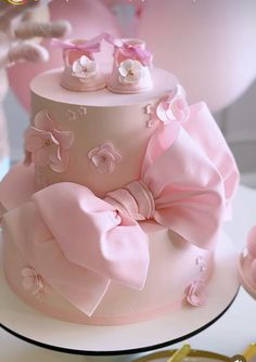 a pink cake decorated with baby shoes and flowers on top is shown in the foreground