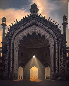 the sun is shining down on an ornate building with pillars and arches in front of it