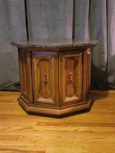 an old wooden cabinet with marble top on the floor