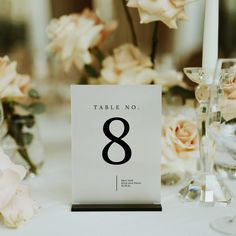 a table number is placed on top of a white table cloth with flowers in the background