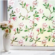 a vase filled with flowers next to a window covered in floral wallpaper and glass