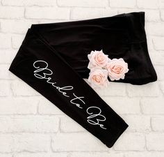 the black leggings with pink roses are on display against a white brick wall