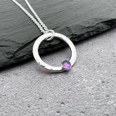 This beautiful purple amethyst and silver circle necklace would make the perfect birthday gift - amethyst being the February birthstone.  A 4mm amethyst gemstone has been set on a hammered circle of sterling silver, which is approximately 20mm in diameter and 2mm wide. This is all made by hand in my studio so minor variations may occur.  Other gemstones are available so please message me with queries or check this link https://etsy.me/33sJuOC The pendant has been hung from a sterling silver chai Sterling Silver Hammered Jewelry Gift, Hammered Sterling Silver Jewelry For Gifts, Hammered Sterling Silver Jewelry Gift, Silver May Birthstone Necklace As A Gift For Her, Sterling Silver Hammered Necklaces For Anniversary, Sterling Silver Hammered Necklace For Anniversary, Hammered Sterling Silver Necklaces For Anniversary, Anniversary Sterling Silver Hammered Necklace, Silver Birthstone Necklace With Ethical Gemstones For Her