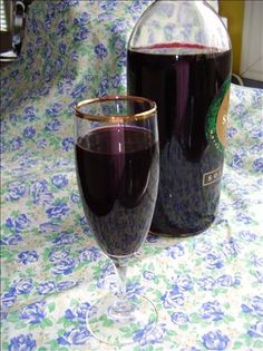 a glass and bottle of wine sitting on a table with a blue flowered cloth