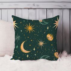 a green pillow with gold stars and moon designs on it, sitting on a white furnishing