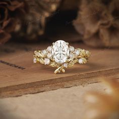 a close up of a ring on top of a wooden surface with flowers in the background