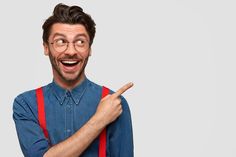 a man with glasses and suspenders pointing to the side while making a funny face