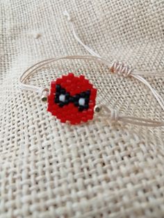 a red beaded object sitting on top of a piece of cloth next to a cord