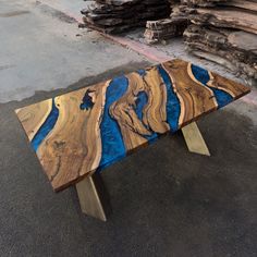 a table made out of wood with blue and gold paint on it sitting in front of logs