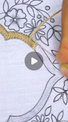 someone is using scissors to stitch the fabric on a piece of cloth with flowers and leaves