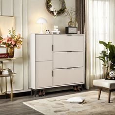 a white cabinet sitting in the middle of a living room next to a chair and table