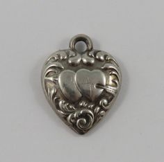 "This is a vintage \"Puffy Heart\" sterling silver charm for a charm bracelet.  It weighs .95 grams and measures 5/8\" X 3/4\", marked \"STERLING\" All charms come with a split ring to attach to a bracelet. We have hundreds of charms in stock. If you don't see what you are looking for in our shop please contact us as it is likely we have it. Inventory #13162" Sterling Silver Heart-shaped Engraved Charm Bracelet, Engraved Heart-shaped Sterling Silver Charm Bracelet, Anniversary Heart Pendant Charm Bracelet, Silver Engraved Heart Charm Bracelet, Vintage Heart Charm Pendant, Silver Engraved Charms For Collectors, Vintage Antique Silver Nickel-free Charms, Collectible Silver Engraved Charms, Vintage Nickel-free Antique Silver Charms