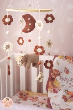 a baby crib with a stuffed animal hanging from it's side and flowers on the top