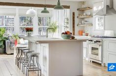 a kitchen with white cabinets and an island in front of the stove, surrounded by bar stools