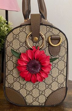 a handbag with a flower on it sitting on a table next to a lamp