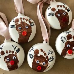 four handprinted ornaments with pink ribbon on them, one is brown and the other is white