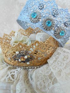 two tiaras sitting next to each other on top of a white lace covered table