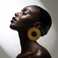 an african woman with her eyes closed wearing large gold hoop earrings on her head, against a white background