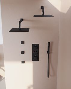 a bathroom with black fixtures on the wall, and a shower faucet in the corner