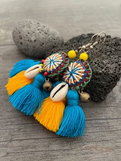 Unique fun and colorful earrings. Made with yellow and blue tassels and a beautiful round center piece made with different fabrics and strings, the earrings are adorned with beads, brass bells and shells. This pair will rock your outfit. Fun and easy to wear as they are super light. The earrings are 6cm- 2.40inch long 5.3cm- 2.10inch wide This timeless pair will brighten up your days! To see more unique and fun colorful tassel earrings, click the link below https://www.etsy.com/shop/AkashiJewelr Yellow Bohemian Earrings With Latkans, Bohemian Yellow Earrings With Latkans, Bohemian Blue Earrings For The Beach, Yellow Bohemian Tassel Earrings For Beach, Bohemian Blue Earrings For Beach, Yellow Tassel Earrings For Festival, Bohemian Beaded Earrings With Latkans For Beach, Handmade Blue Bohemian Tassel Earrings, Adjustable Yellow Bohemian Tassel Earrings