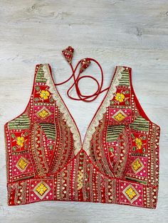 Red multicolored embroidered sleeveless blouse features thread & mirror work, hook closure & tie-up at the back. Team this blouse with a contrasting saree to look gorgeous and create a stunning and beautiful look. Buy this designer blouse in the USA from Pure Elegance. Disclaimer: The actual product may vary slightly from the image. These are custom orders, hence expect slight variation in color, and placement of the motif, or buta. ESTIMATED DELIVERYBecause this is a custom order, it would take about 2 weeks from the date of purchase. RETURN POLICY: This product is a custom order and cannot be returned or exchanged. Sleeveless Traditional Wear With Mirror Work, Red Zari Work Saree For Festival, Red Saree With Zari Work For Festival, Bohemian Sleeveless Blouse With Zari Work, Sleeveless Bohemian Blouse Piece With Zari Work, Sleeveless Blouse With Multicolor Embroidery For Festivals, Red Summer Traditional Wear With Zari Work, Summer Red Traditional Wear With Zari Work, Red Traditional Wear With Zari Work For Summer