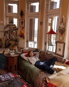 a man laying on top of a couch in a living room next to two windows