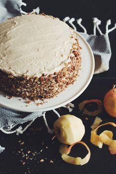 a cake sitting on top of a white plate next to sliced apples and other fruit