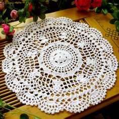 a crocheted doily sitting on top of a wooden table next to flowers