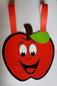 a red apple with a green leaf on it's head hanging from a hook