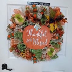 a wreath that says, thank you and is hanging on the front door with an orange pumpkin