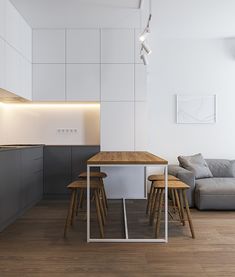 a modern kitchen and living room with white walls, wood flooring and grey furniture