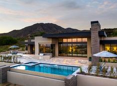 a house with a swimming pool in front of it and mountains in the back ground