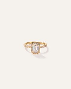 a gold ring with an emerald stone and diamonds on the band, set in 18k yellow gold