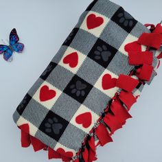 a butterfly is sitting next to a blanket with hearts on it and a dog paw print