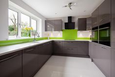 an empty kitchen with green accent wall and white counter tops, along with gray cabinets