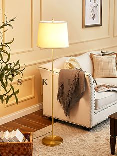 a living room with a white couch and a lamp on the floor next to a coffee table